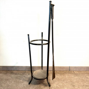 A wrought-iron umbrella stand with a forged shoehorn
