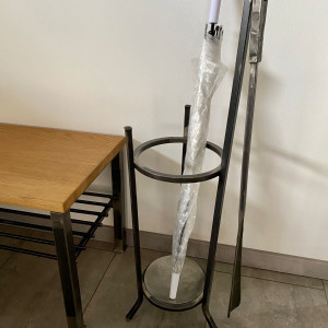 A wrought-iron umbrella stand with a forged shoehorn