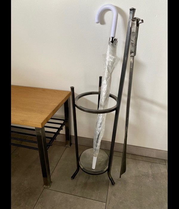 A wrought-iron umbrella stand with a forged shoehorn