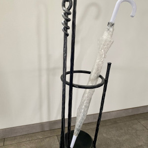 A wrought-iron umbrella stand with a shoehorn